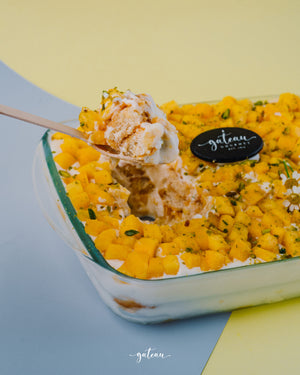 Mango tiramisu dessert topped with fresh mango cubes in a clear glass dish from Gateau Gourmet Cafe
