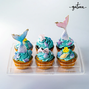 Gateau Gourmet Cafe mermaid theme cupcakes with blue frosting and seashell decorations on clear tray