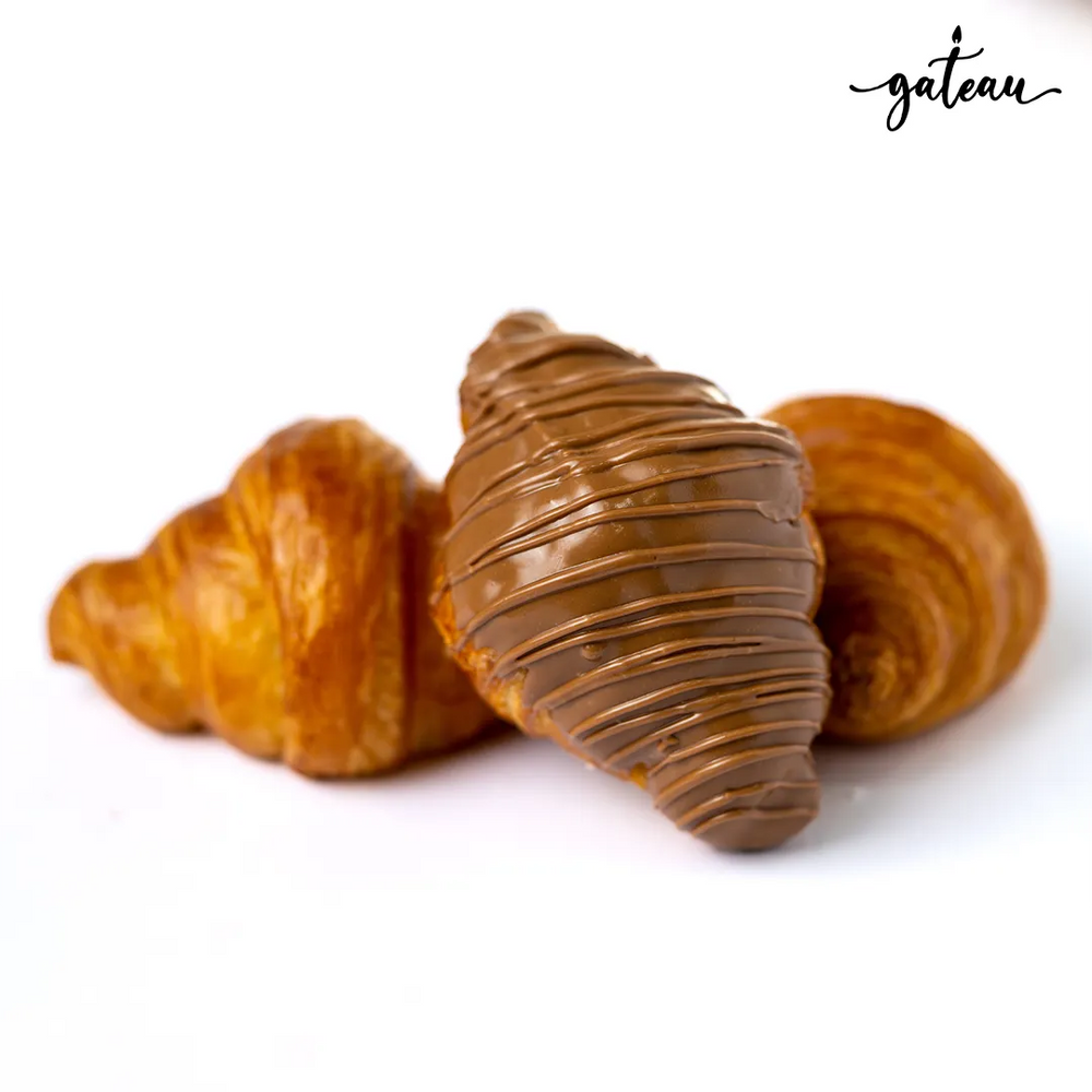 Milk chocolate croissant drizzled with creamy milk chocolate next to plain croissants from Gateau Gourmet Cafe