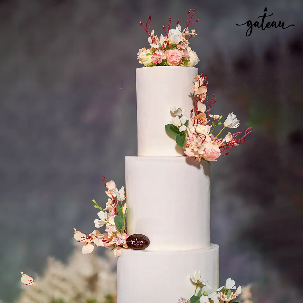 Minimalist wedding cake with flowers featuring three smooth white tiers and delicate floral decorations