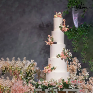 Minimalist wedding cake with flowers by Gateau Gourmet Cafe featuring five white tiers decorated with soft pink floral accents