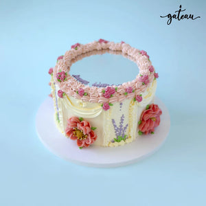 Gateau Gourmet Cafe mirror glaze cake with floral decorations and pink frosting swirls on a white base