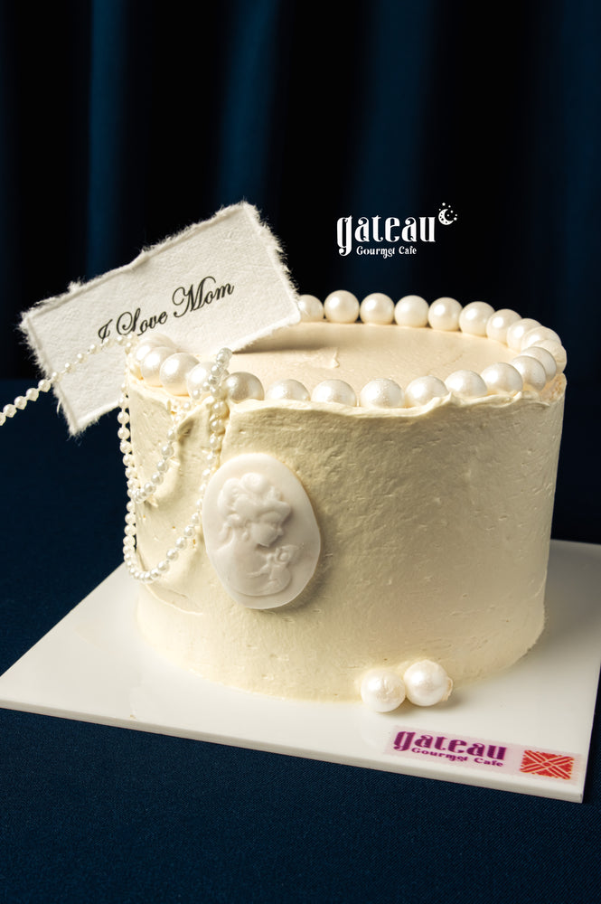 Elegant white Mother's Day cake delivery from Gateau Gourmet Cafe decorated with pearls and a Love Mom tag