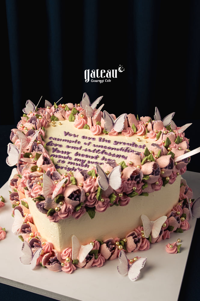Mother's Day heart-shaped cake by Gateau Gourmet Cafe decorated with pink flowers and edible butterflies