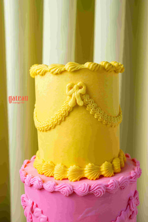 Two-tier cake with yellow and pink frosting from Gateau Gourmet Cafe order gourmet cakes online