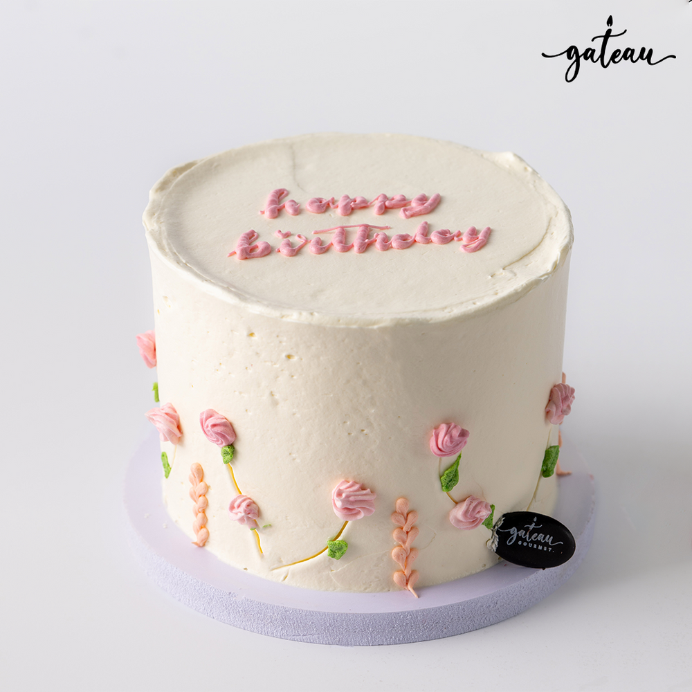 Pastel rose birthday cake with pink floral decorations and happy birthday text on top