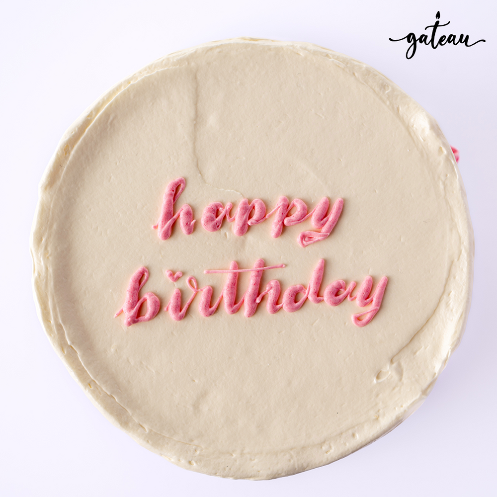 Pastel rose birthday cake with smooth white frosting and pink happy birthday text decoration
