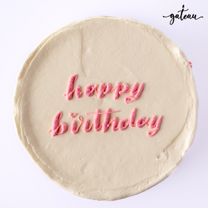 Pastel rose birthday cake with smooth white frosting and pink happy birthday text decoration