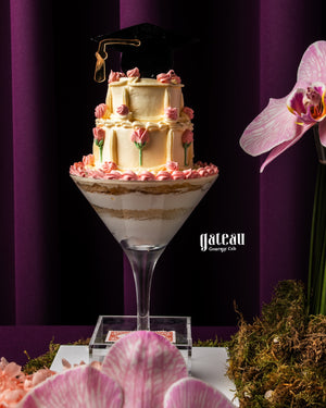Elegant personalized graduation cake with a graduation cap, pink frosting, and layered design