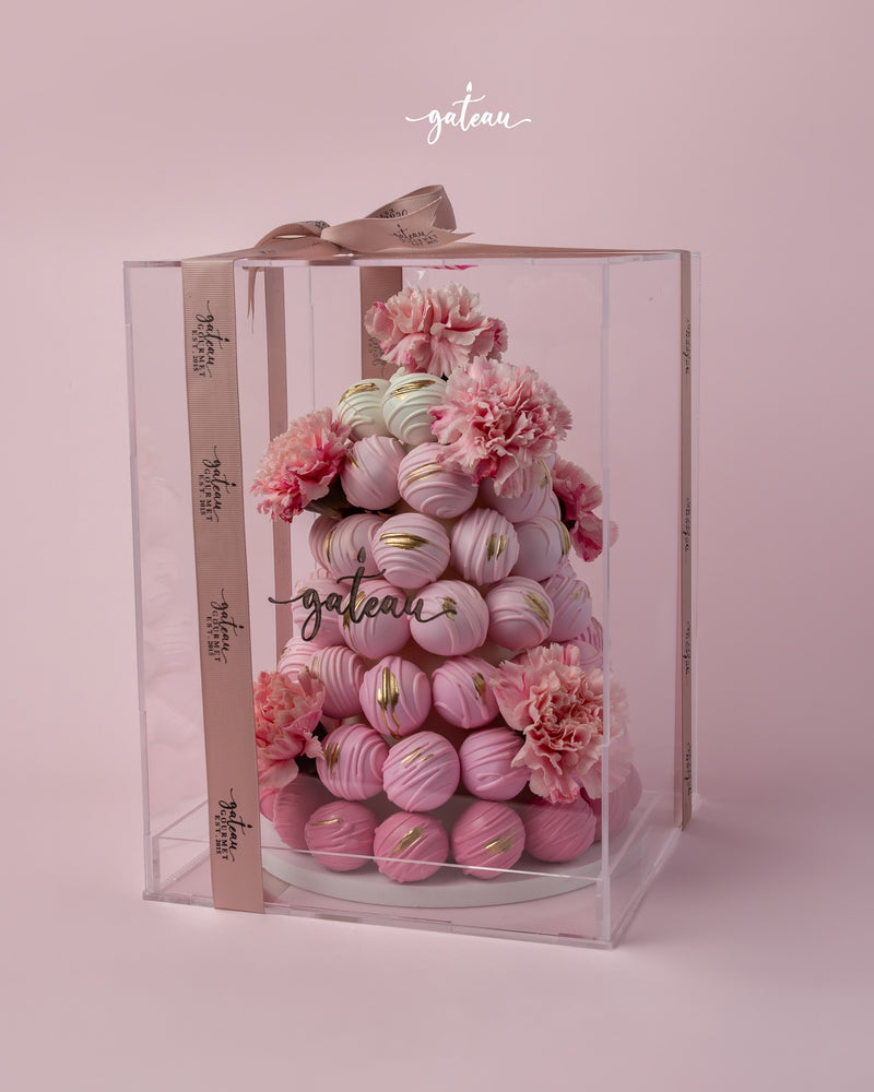 Elegant pink chocolate truffle arrangement with delicate flowers in a clear display box