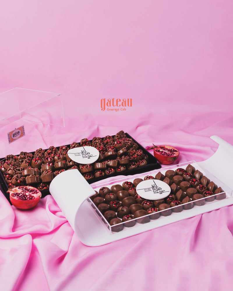 Gourmet pomegranate chocolate set featuring assorted chocolate pieces on a pink background