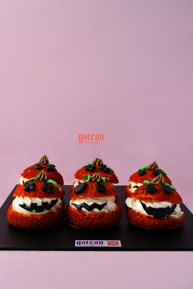 Festive pumpkin choux pastry decorated like pumpkins with cream and chocolate accents