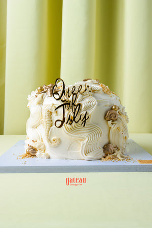 Queen of July birthday cake by Gateau Gourmet Cafe with white frosting and decorative seashells