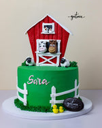 Rainbow garden theme cake featuring a red barn and adorable animal figurines for a festive celebration