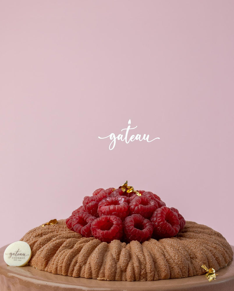 Raspberry chocolate roll cake decorated with fresh raspberries and gold accents from Gateau Gourmet Cafe