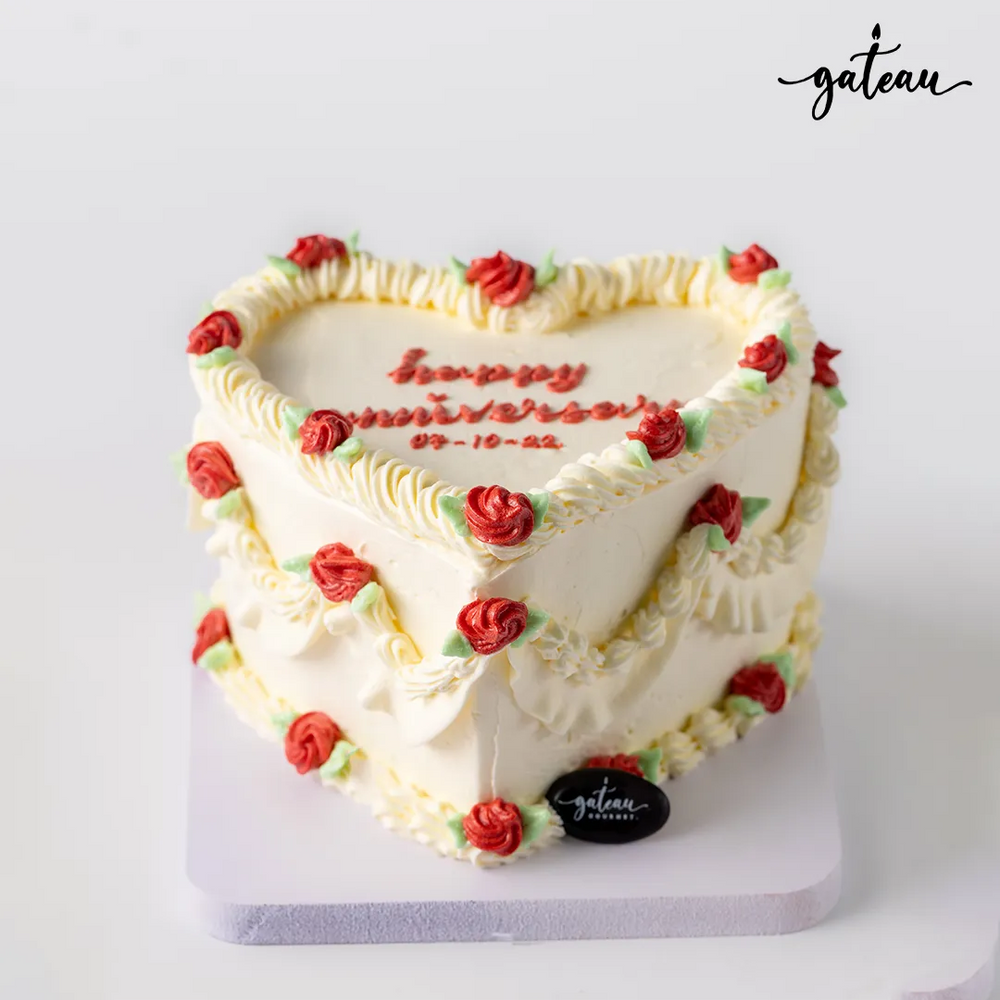 Romantic custom cake for couples by Gateau Gourmet Cafe heart-shaped with white frosting and red rose decorations