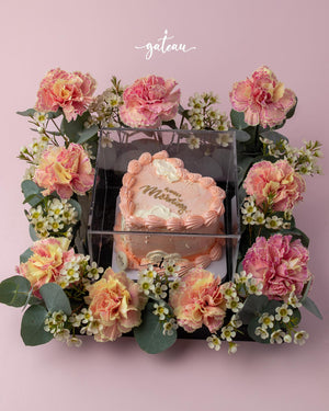 Romantic floral cake arrangement by Gateau Gourmet Cafe featuring a heart-shaped cake surrounded by pink and yellow flowers