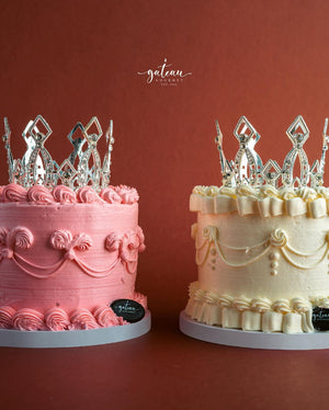 Gateau Gourmet Cafe royal crown cake in pink and white with intricate frosting and silver crown toppers