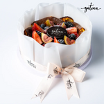 Gateau Gourmet Cafe San Sebastian cheesecake topped with fresh strawberries, figs, blackberries, and blueberries wrapped in parchment paper