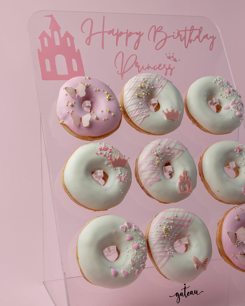 Gateau Gourmet Cafe special occasion donut treats decorated with pink and white icing and gold sprinkles on a birthday display