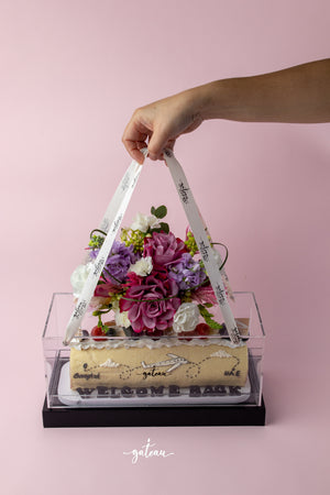 Special occasion Swiss roll from Gateau Gourmet Cafe decorated with flowers in a clear gift box with handle