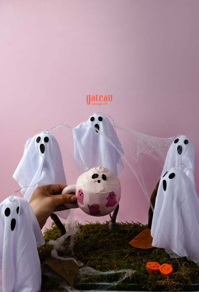 Spooky cake in a cup surrounded by playful ghost decorations for Halloween treats