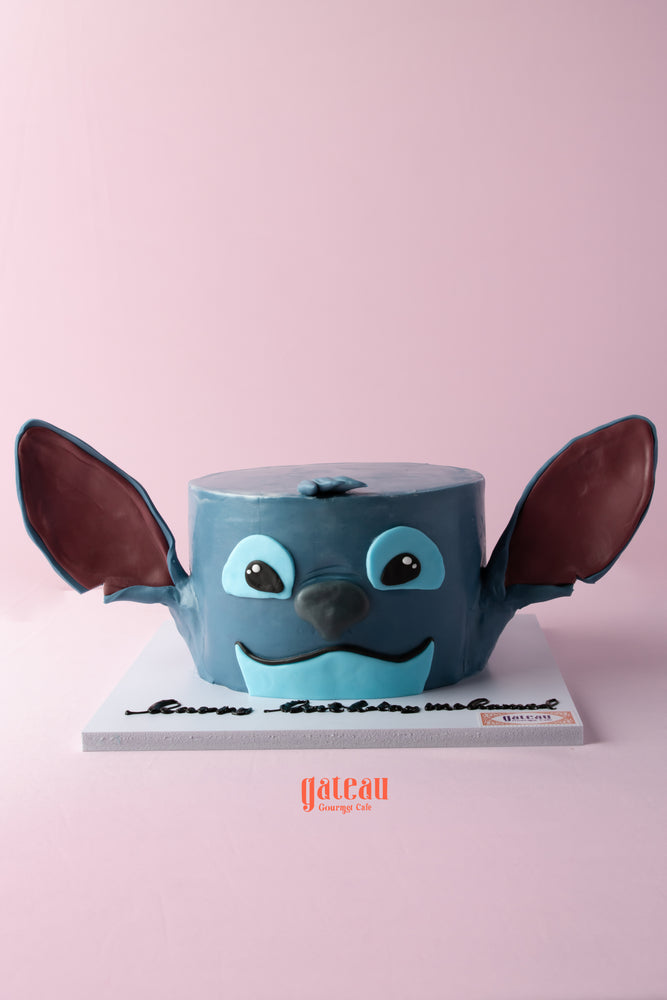 Stitch themed cake in blue with large ears and facial features, perfect for themed parties