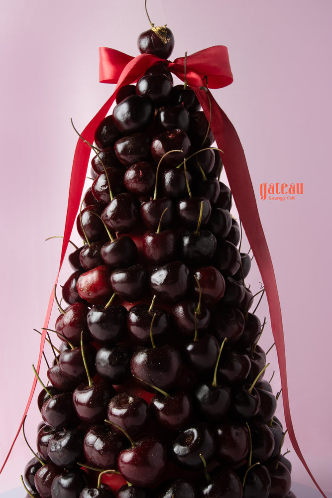 Delicious strawberry and cherry dessert tower adorned with a ribbon, featuring fresh cherries stacked beautifully