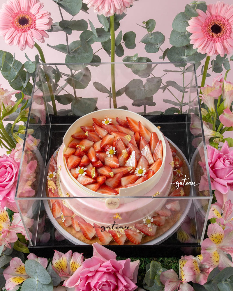 Elegant strawberry mousse cake arrangement topped with fresh strawberries and delicate flowers