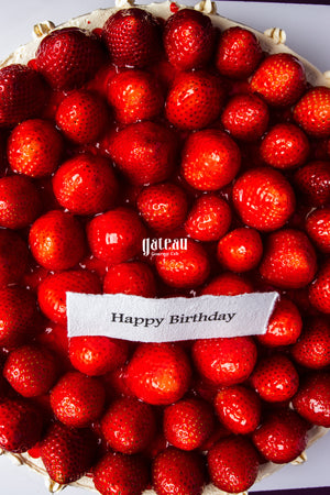 Gateau Gourmet Cafe strawberry sponge cake for celebration topped with fresh whole strawberries and Happy Birthday message