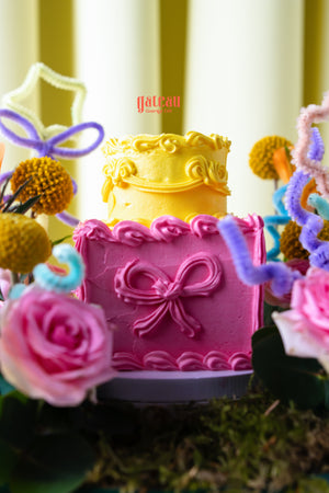 Summer buttercream flower cake by Gateau Gourmet Cafe with yellow and pink frosting and floral decorations
