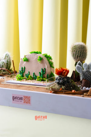 Summer cactus cake by Gateau Gourmet Cafe decorated with green cactus designs and moss accents