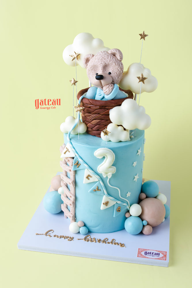 A cute teddy bear birthday cake with clouds, stars, and pastel decorations from Gateau Gourmet Cafe