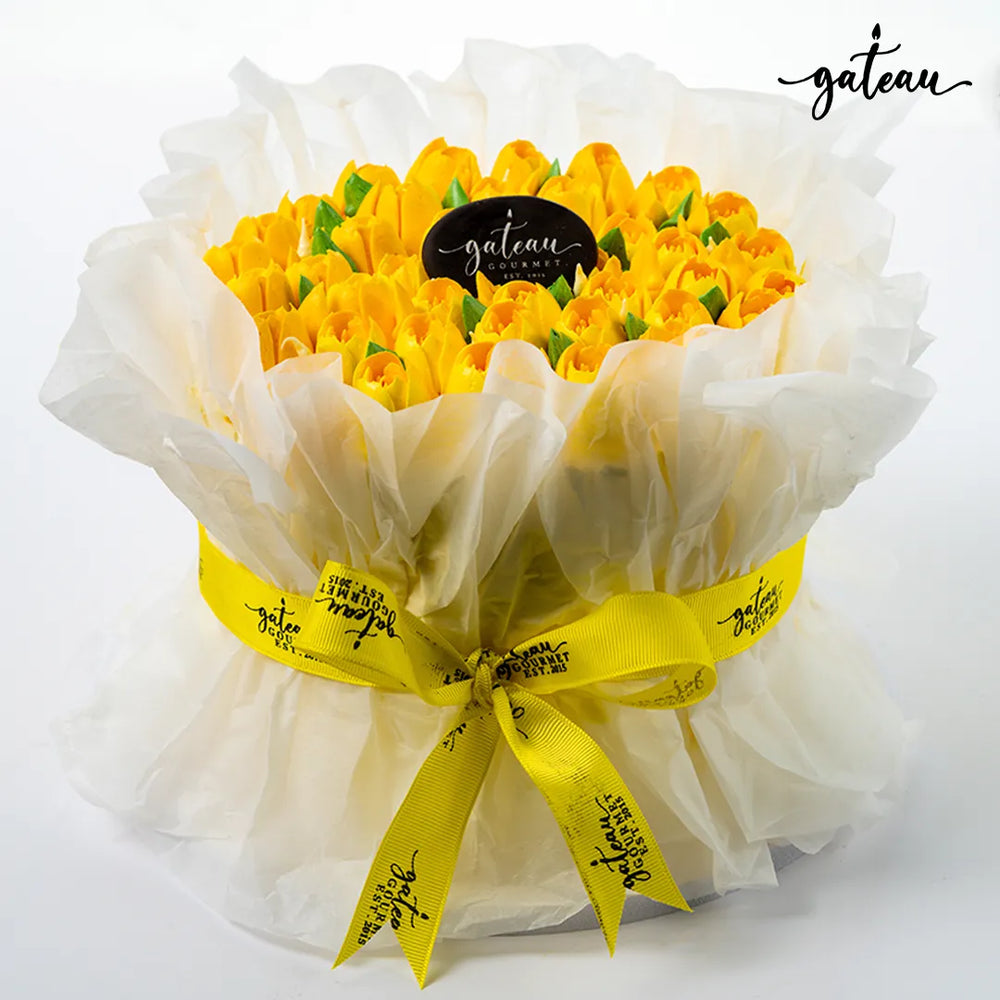 Gateau Gourmet Cafe tulip flower cake with yellow tulip-shaped frosting wrapped in white translucent paper and yellow ribbon