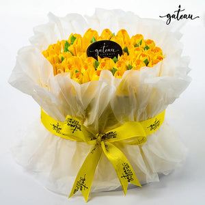 Gateau Gourmet Cafe tulip flower cake with yellow tulip-shaped frosting wrapped in white translucent paper and yellow ribbon