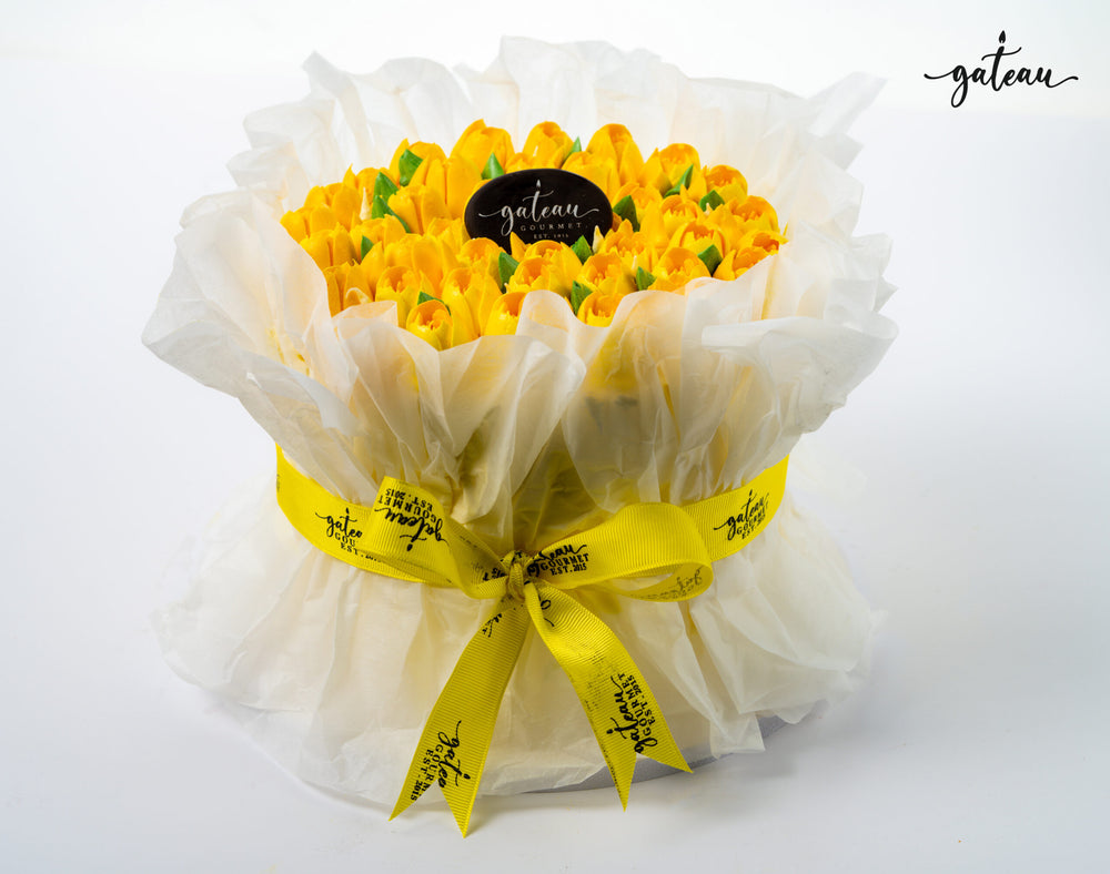 Gateau Gourmet Cafe yellow tulip flower cake wrapped in white paper with yellow ribbon