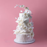 Elegant white tiered wedding cake with intricate floral decorations showcasing unique wedding cake designs by Gateau Gourmet Cafe