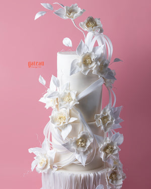 Elegant white tiered wedding cake with delicate floral decorations showcasing unique wedding cake designs by Gateau Gourmet Cafe