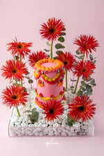 Vibrant floral cake arrangement with bright red flowers and pink decorative cake by Gateau Gourmet Cafe