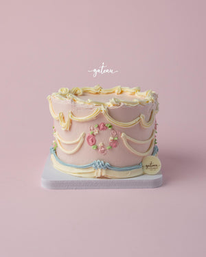 Vintage Buttercream Drape Cake with colorful floral decorations and elegant draping on a light pink background.