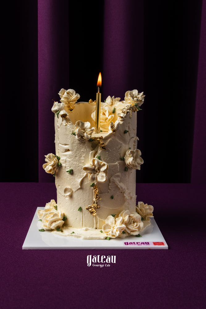 Gateau Gourmet Cafe white garden candlelight arrangement cake with elegant floral decorations and single lit candle