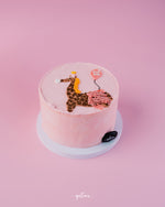 Pink birthday cake with giraffe cake design for birthday featuring balloon and crown decoration
