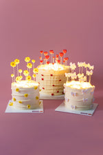 Three Glow in the Dark Birthday Cakes decorated with edible flowers for vibrant celebrations