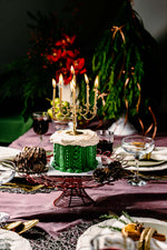 Gateau Gourmet Cafe Gold Candle Labra Cake Design with green frosting and white top on festive table