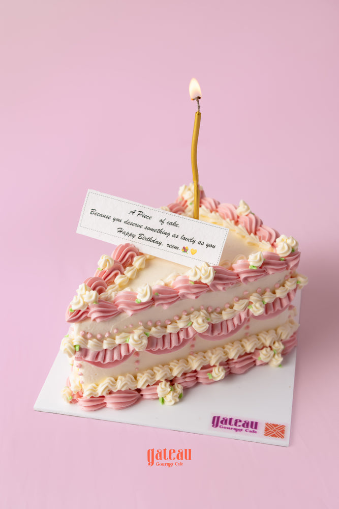 Delicious gourmet birthday cake from Gateau Gourmet Cafe decorated with pink frosting and a candle for celebrations.