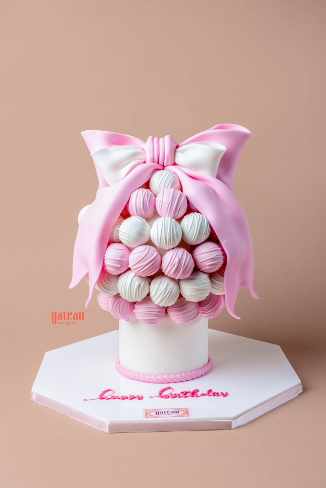 Gourmet birthday truffle cake decorated with pink and white truffles and a large bow on top