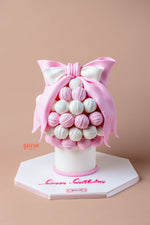 Gourmet birthday truffle cake decorated with pink and white truffles and a large bow on top