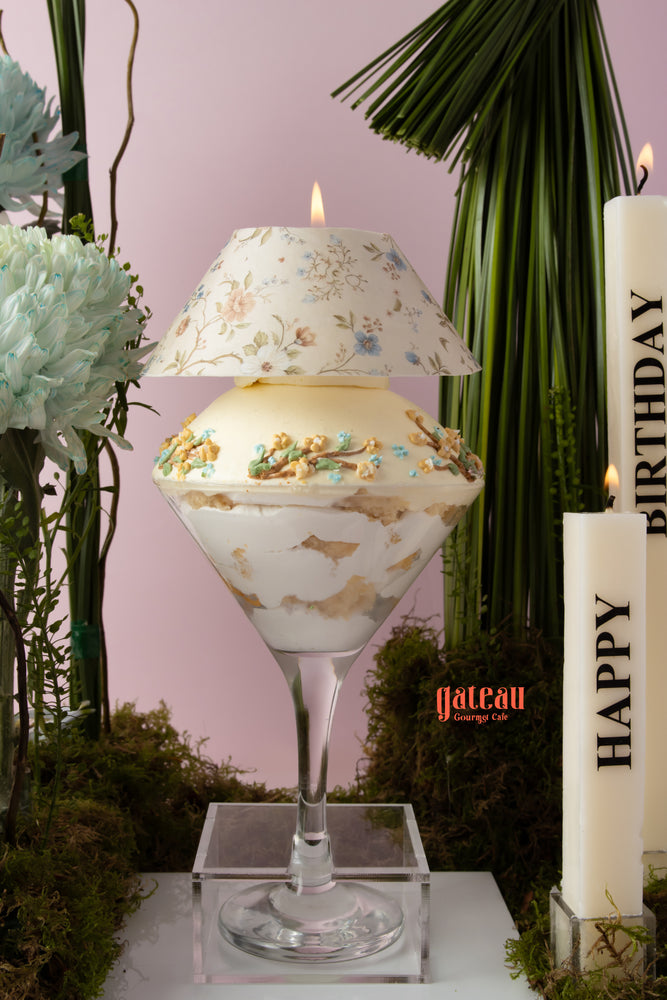 Elegant gourmet cake with bouquet displayed in a decorative glass with candles for a birthday celebration