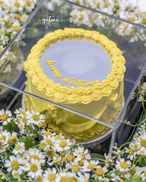 Yellow gourmet mirror cake with birthday decoration in clear box for gourmet mirror cake delivery by Gateau Gourmet Cafe