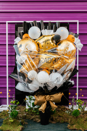 A vibrant graduation balloons bouquet featuring gold and black balloons with celebratory messages for graduation parties